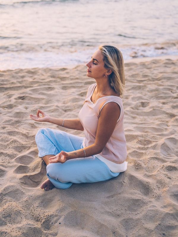 Person meditating peacefully in a yoga pose outdoors at sunset.